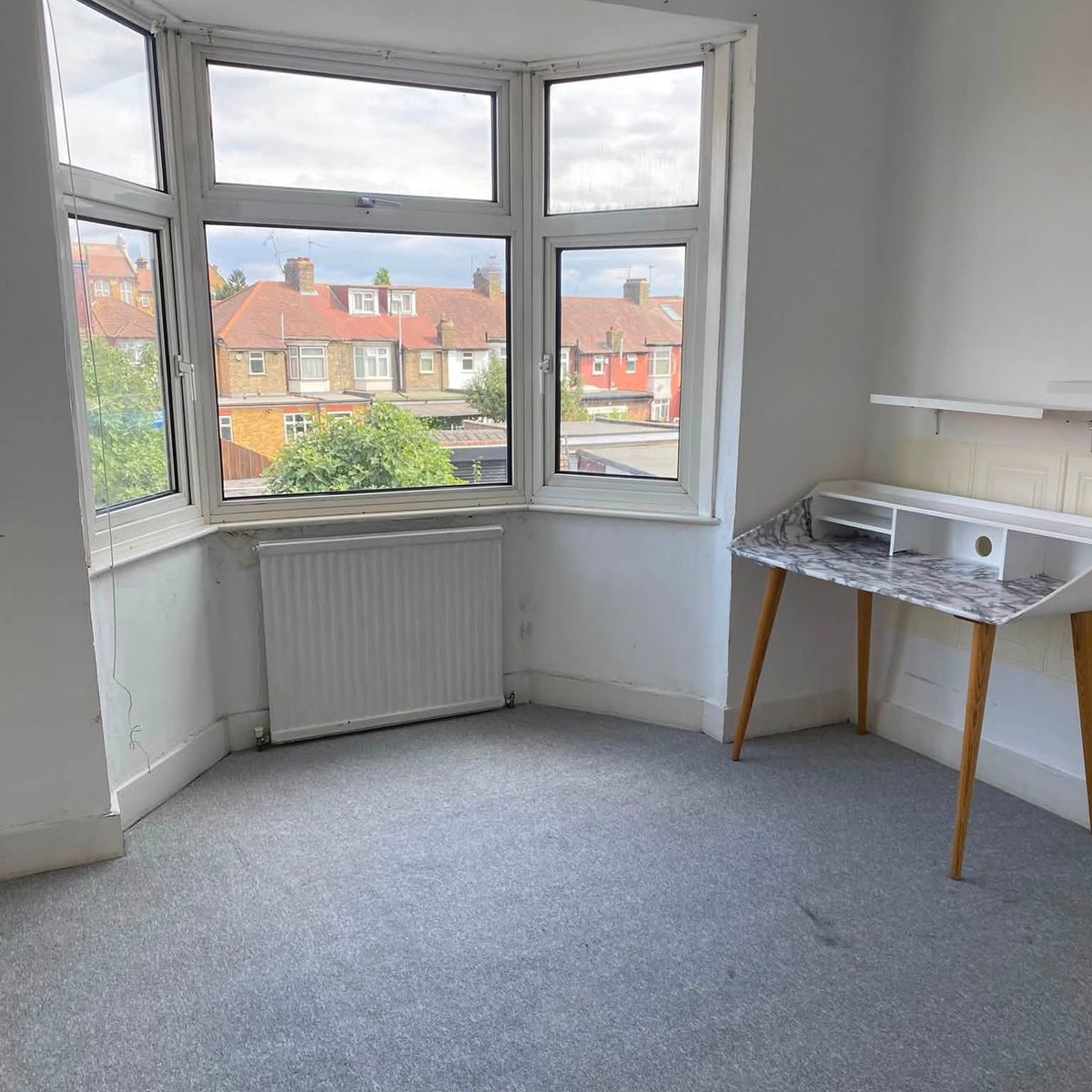 Bedroom with a bay window and vacuumed grey carpet